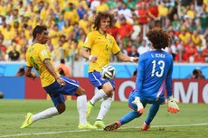 Com os braços junto ao corpo, Ochoa sai do gol e salva conclusão de Paulinho em lance que aparece também David Luiz, na Copa de 2014